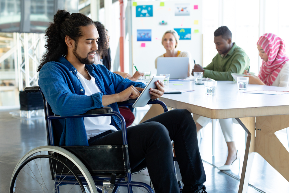 Front view of Mixed-race disabled businessman using digital tablet in conference room during meeting in a modern office